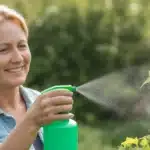Kobieta spryskuje rośliny naturalnym opryskem z sody i octu na mszyce w ogrodzie