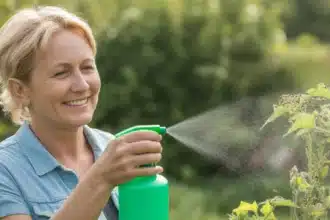 Kobieta spryskuje rośliny naturalnym opryskem z sody i octu na mszyce w ogrodzie
